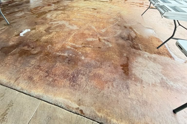 Outdoor event pavilion with blotchy, discolored stained concrete before resurfacing